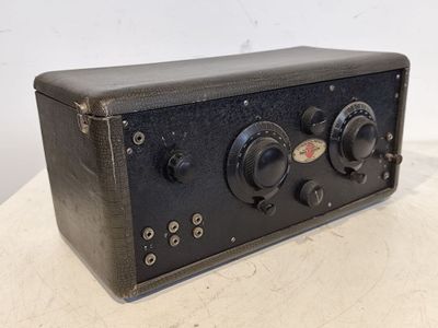 une vieille radio noire posée sur une table près d'un mur blanc
