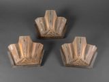 trois appliques en verre posées sur une surface grise, sur fond gris