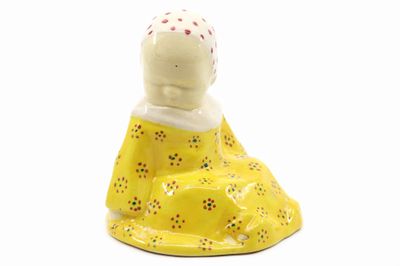 une petite figurine représentant une femme en robe jaune