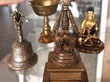 une table en verre sur laquelle sont posées trois statues en laiton et un bol