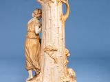 a statue of a man and a woman standing next to a tall tree