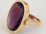 a close up of a ring with a purple stone in it