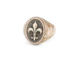 un gros plan d'une bague ornée d'une fleur de lys
