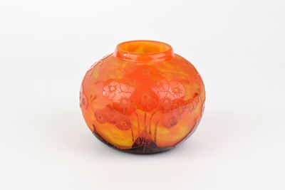un vase orange posé sur une surface blanche