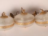 trois boules de Noël en verre blanc et doré posées sur un fond blanc