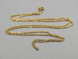 un collier en or avec une chaîne posée sur une surface grise