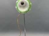 une lampe verte et blanche posée sur un pied en métal