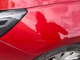 a red car with a person in a hoodie standing in front of it