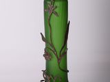 a green glass vase with a metal decoration on it