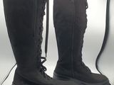 pair of black boots with laces on them sitting in front of a light