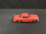 a small red toy car on a black surface