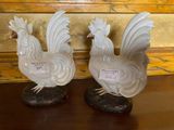 two white rooster figurines sitting on a table
