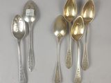 quatre cuillères en argent et une cuillère en argent posées sur une surface blanche
