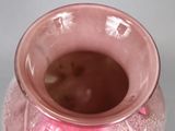 a pink vase sitting on a table with a white background