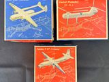 trois boîtes contenant des maquettes d'avions, posées sur une surface noire