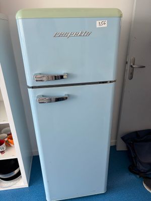 un petit réfrigérateur bleu dans un coin de la pièce