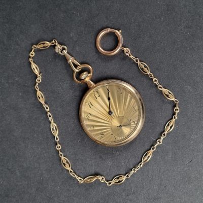 une montre de poche en or, suspendue à une chaîne, posée sur une table