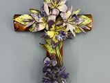 des fleurs violettes et jaunes sur une croix en bois accrochée au mur