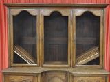 a wooden cabinet with glass doors and a red curtain in the background