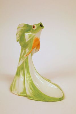 une figurine de poisson verte et orange posée sur une surface blanche