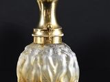 an image of a glass vase with a gold top on a black surface