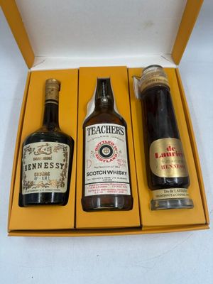 three bottles of alcohol in a yellow box on a white surface
