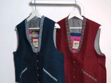 two vests hanging on a clothes rack in a room