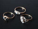 trois bagues en or ornées de diamants et d'une perle sur un fond noir