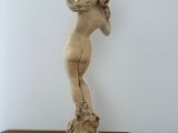 statue of a woman on a wooden table with a white wall in the background