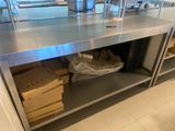 un grand plan de travail en inox dans une cuisine, sur lequel sont posées des boîtes