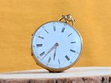a gold pocket watch sitting on top of a piece of wood