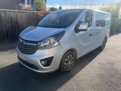 La camionnette argentée est garée dans la rue, devant une clôture en bois.