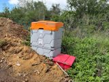 une glacière orange et grise posée sur un tas de terre, à côté d'un autre tas de terre