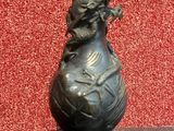 un vase en bronze orné d'un oiseau, posé sur une table