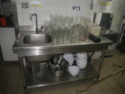 a stainless steel sink in a kitchen with dishes on the counter