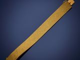 un gros plan d'un bracelet doré sur fond bleu