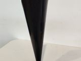 a black vase on a white table with a white background