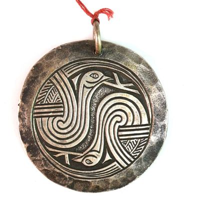 une photo d'un pendentif en argent sur lequel figure un oiseau