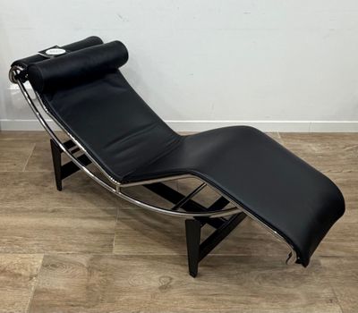 une photo d'une chaise longue en cuir noir posée sur un parquet