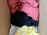 a cardboard box filled with clothes and a pink shirt