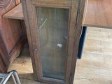 a wooden cabinet with a glass door and a chair in front of it