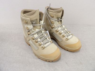 une paire de chaussures de randonnée beiges à lacets posée sur une surface blanche
