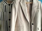 deux vestes accrochées à une porte bleue, à côté d'une paire de chaussures