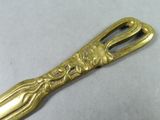 a gold spoon with a gold handle on a white surface