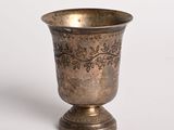 un vase en argent posé sur une surface blanche