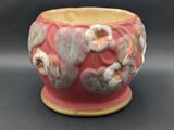 a pink vase with white flowers on it on a table