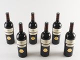 six bottles of wine are lined up in a row on a white surface