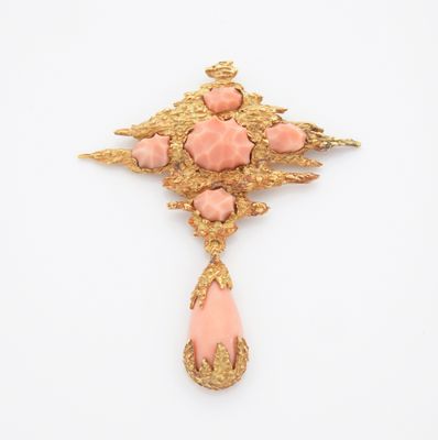 un pendentif-broche rose et doré orné d'un motif floral