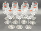 six clear wine glasses with orange labels are lined up on a table