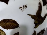a white vase with brown leaves and birds on it